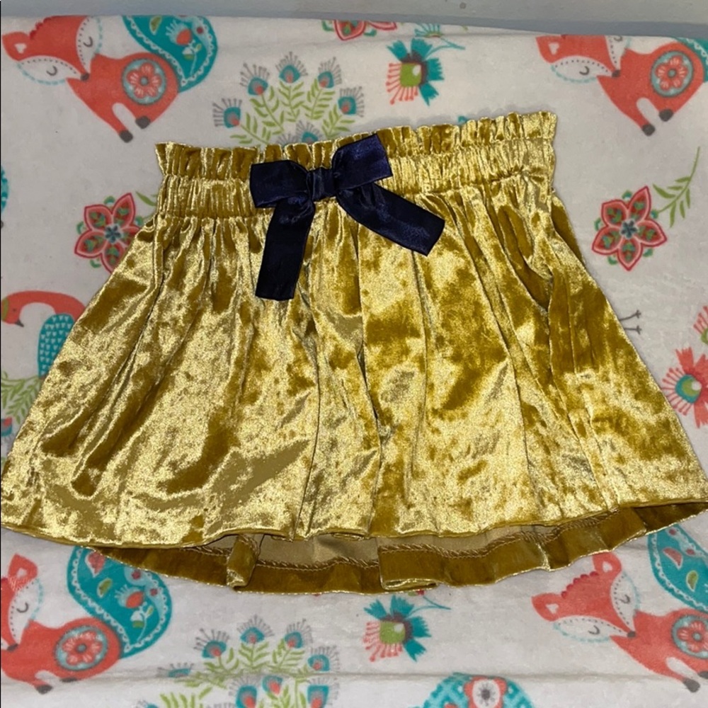 Super cute gold skirt with dark purple bow.